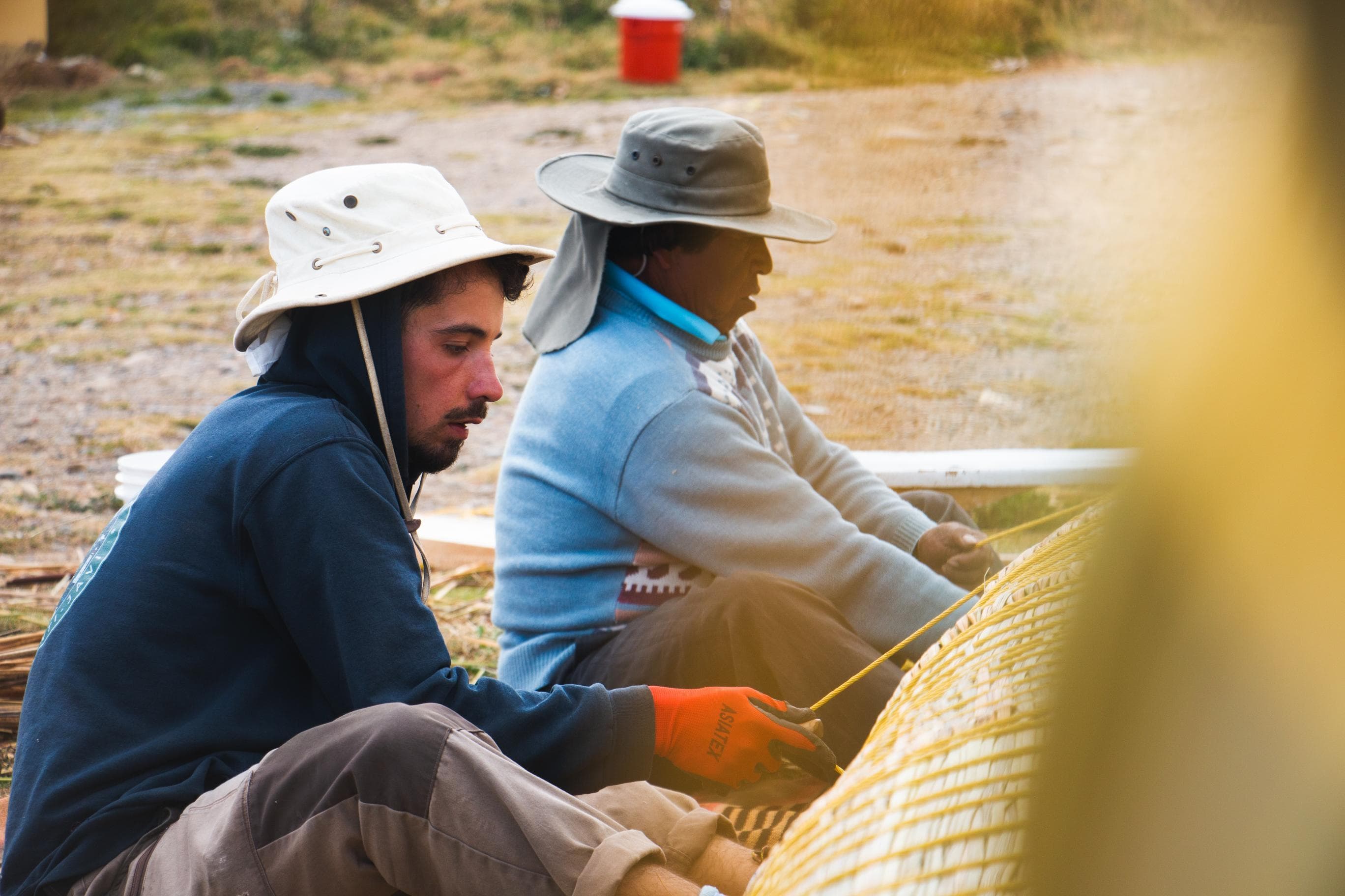 Un équipier et un artisan aymara ligaturent ensemble une botte de totora pendant la construction de la balsa